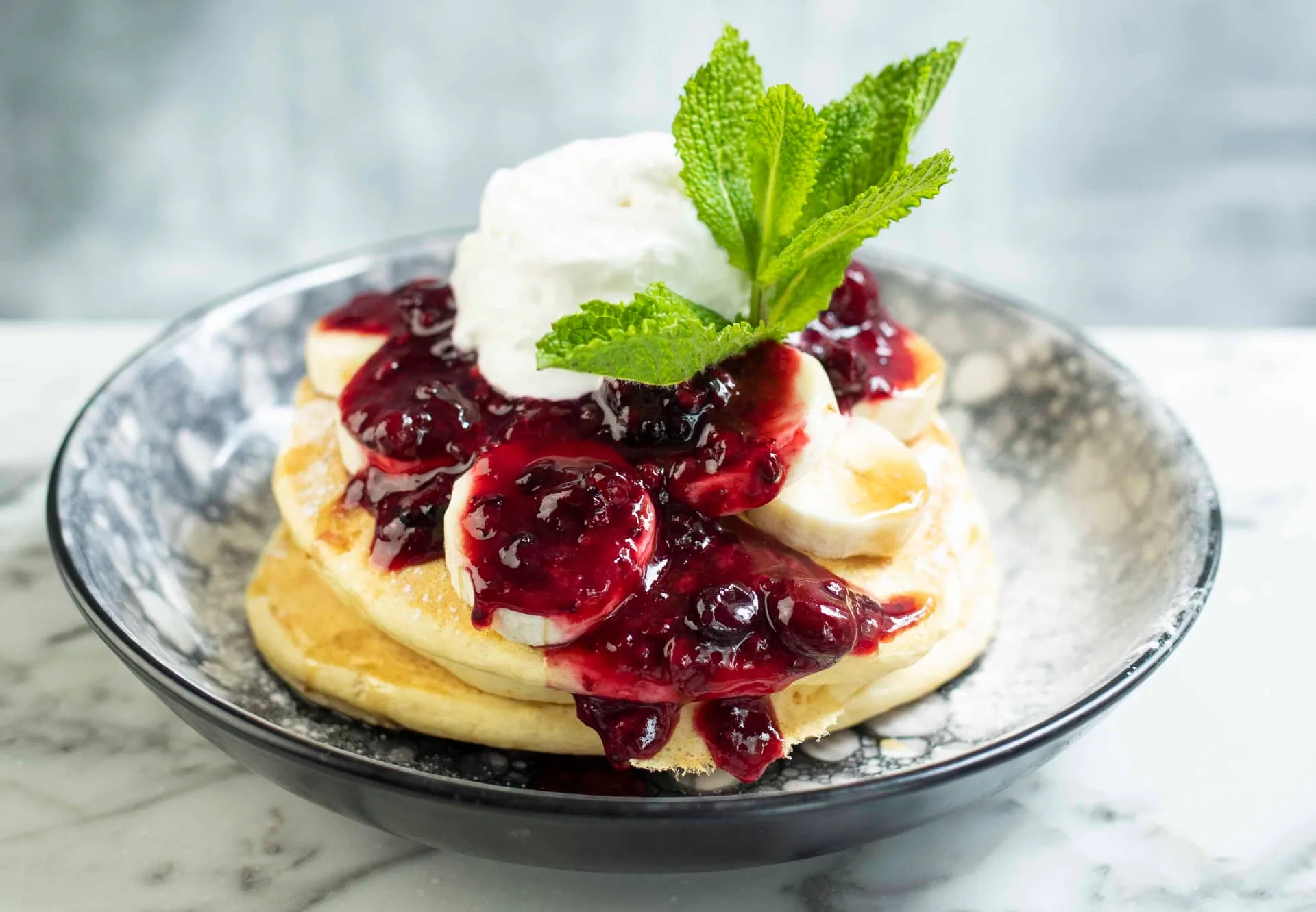 Stapel pannenkoeken met banaan, bessen en jam van WAKU WAKU