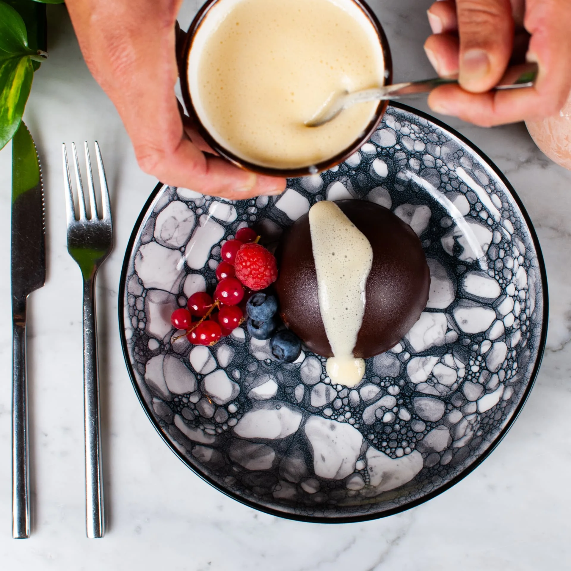 Plantaardig chocoladedessert met bessen waar saus overheen wordt geschonken