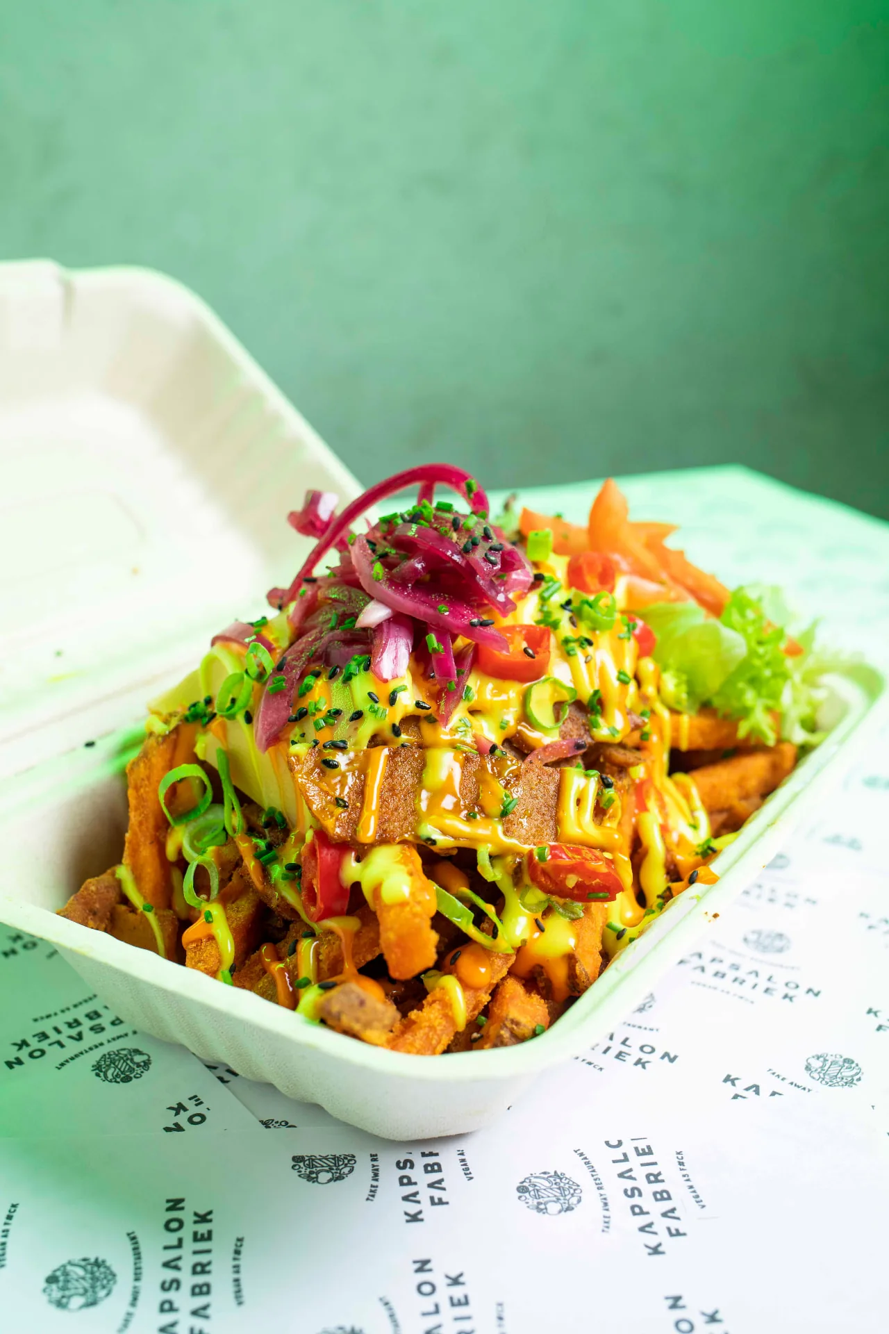 Volledig plantaardige kapsalon in een afhaalbak met rode ui en saus