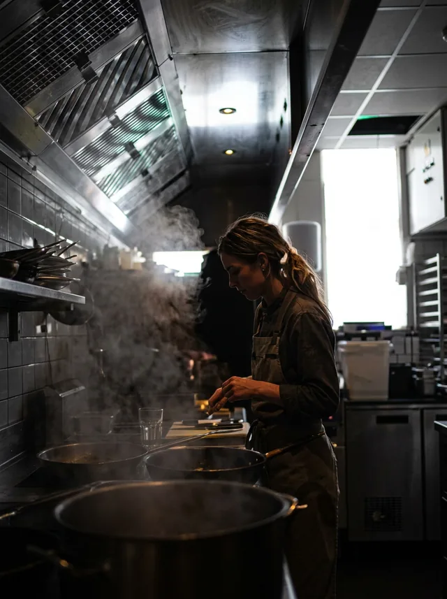 Kok aan het werk achter een pan met stoom in de keuken van WAKU WAKU
